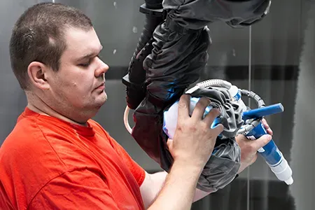 Muž operující robotický lakovací systém