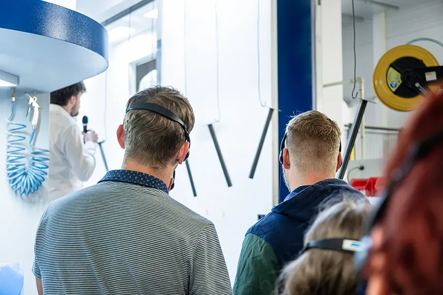 Muži poslouchající prezentaci v industriální lakovně