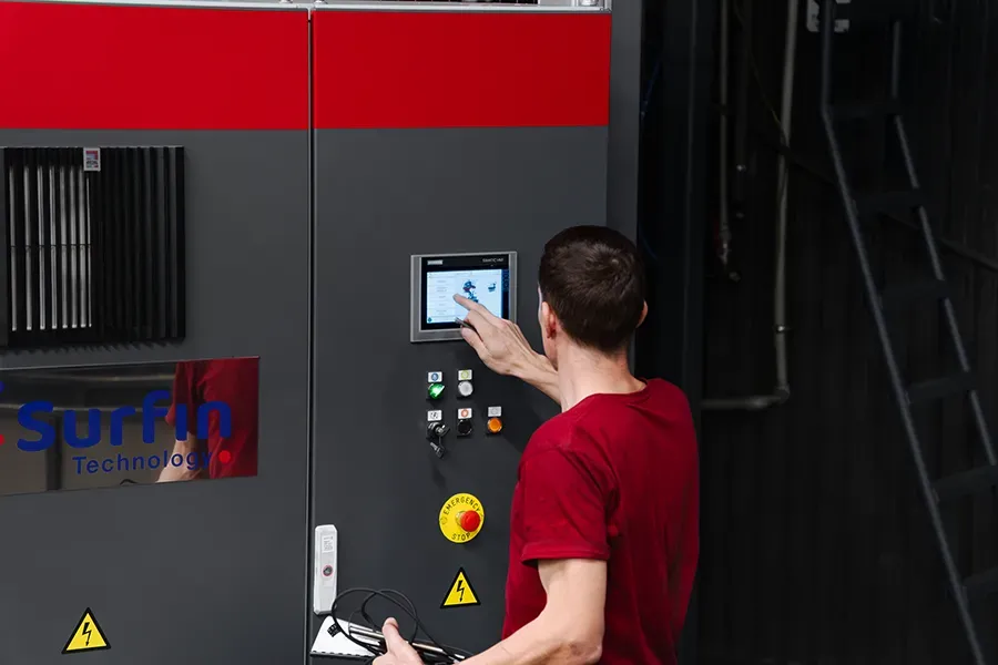 Technician operating carousel blasting machine